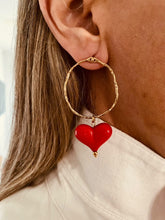 Load image into Gallery viewer, These handcrafted stainless steel earrings showcase a distinctive, irregular hollow circle that hangs gracefully above a vibrant acrylic heart, available in bold red or soft white. The heart dangles elegantly below the circle, creating a playful yet modern contrast that adds a touch of color and movement to any look. Lightweight, durable, and full of personality, these earrings combine geometric precision with artistic flair, making them the perfect accessory to elevate your style for any occasion.