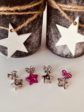 Load image into Gallery viewer, Star-shaped earrings on a white surface with two jars in the background.