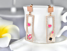 Load image into Gallery viewer, Add a playful touch to your look with these makeup elements pink lips & lipstick earrings. Crafted from rose gold color stainless steel, these charming earrings feature a fun design of pink lips and a lipstick adorned with sparkling rhinestones. Perfect for beauty lovers, they combine durability with a touch of glamour, making them a unique accessory for any outfit or a thoughtful gift for someone special.