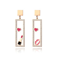 Load image into Gallery viewer, Add a playful touch to your look with these makeup elements pink lips & lipstick earrings. Crafted from rose gold color stainless steel, these charming earrings feature a fun design of pink lips and a lipstick adorned with sparkling rhinestones. Perfect for beauty lovers, they combine durability with a touch of glamour, making them a unique accessory for any outfit or a thoughtful gift for someone special.