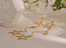 Load image into Gallery viewer, Shine bright with these fashion star long drop dangle earrings, a dazzling addition to any jewelry collection. Adorned with two larger star contours and two smaller star charms, these earrings are beautifully crafted from stainless steel and plated in 18K gold for a radiant, luxurious finish. Their elongated design offers graceful movement and a striking silhouette, perfect for adding a touch of glamour to any outfit.