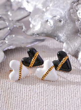 Load image into Gallery viewer, These trendy heart stud earrings feature a chic black or white enamel finish, adorned with a delicate golden chain that adds a unique touch of elegance. Crafted from high-quality 18K plated stainless steel, they exude lasting charm and sophistication. Their romantic design combines classic style with a modern twist, making them a perfect accessory for women who love eye-catching yet versatile jewelry.