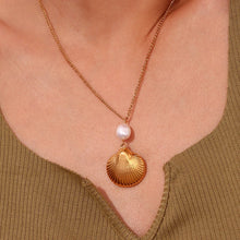 Load image into Gallery viewer, This bohemian stainless steel necklace comes in a 18K plated gold colour. It is adorned with a beautiful shell pendant and a little natural freshwater pearl on top of it. This necklace can perfectly spice up your evening summer outfit . It has lobster clasp and adjustable chain.