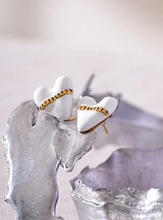 Load image into Gallery viewer, These trendy heart stud earrings feature a chic black or white enamel finish, adorned with a delicate golden chain that adds a unique touch of elegance. Crafted from high-quality 18K plated stainless steel, they exude lasting charm and sophistication. Their romantic design combines classic style with a modern twist, making them a perfect accessory for women who love eye-catching yet versatile jewelry.