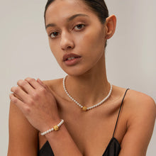 Load image into Gallery viewer, This elegant, vintage-inspired bracelet is crafted from lustrous pearls and features a striking gold-tone hammered stainless steel ball, adding a touch of timeless sophistication. The intricate detailing of the embossed ball beautifully complements the classic pearl design, making this bracelet the perfect accessory for any glamorous or elegant outfit. Finished with a secure lobster clasp and an adjustable chain, it ensures a comfortable and customizable fit.