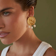Load image into Gallery viewer, These sophisticated earrings are crafted from stainless steel with a luxurious gold finish. Designed in an elegant circular shape with a hammered texture, they feature three delicate artificial pearls gracefully hanging from each hoop. Perfect for elevating any evening ensemble, these earrings add a touch of timeless charm to special occasions. Secure and comfortable with stud fastenings, they are a versatile addition to your jewelry collection, combining classic style with modern elegance.