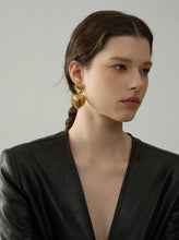 Load image into Gallery viewer, These romantic drop earrings feature an enchanting design with a larger heart gracefully dangling from a smaller one, each crafted from hypoallergenic stainless steel and plated in radiant 18K gold or classic silver. The textured surface and intricate edges add depth and charm, creating an eye-catching look that's both elegant and playful.