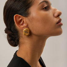 Load image into Gallery viewer, Add a touch of elegance and sparkle to your style with these 18K gold plated stainless steel cross line inlaid rhinestone stud earrings. Featuring a sleek cross-line design adorned with shimmering rhinestones, these earrings are perfect for adding a sophisticated finish to any look. Crafted from durable stainless steel with a radiant gold plating, they offer long-lasting shine and tarnish resistance.