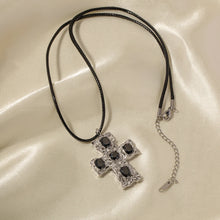 Load image into Gallery viewer, This glam rock necklace is made of stainless steel pendant which is hanging on a black wax rope. The beautiful cross pendant comes in two colours: gold and silver. It has irregular surface which is additionally adorned with 5 big cubic zirconia. It is a perfect piece for any daily occasion as well a great gift for your beloved friend. The necklace has lobster clasp and adjustable chain.