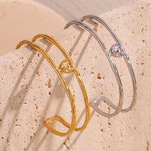 Load image into Gallery viewer, Elevate your style with this charming double layer hollow open bangle bracelet, a stunning piece that adds a touch of romance to any outfit. 18K gold plated for a luxurious finish, this bracelet features a delicate red enamel heart at the center, making it the perfect blend of elegance and playfulness. Available in both gold and silver colors, it's a versatile accessory that can easily complement any look, from casual to chic.