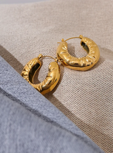 Load image into Gallery viewer, These elegant, chunky hoop earrings are crafted from durable stainless steel with a radiant gold finish, designed to bring a touch of sophistication to everyday looks. Featuring a unique crumpled texture along the edges, they add a modern twist to the classic hoop, making them a standout piece for any occasion. Lightweight yet bold, these hollow hoops are perfect for daily wear and make a thoughtful gift for any woman who appreciates stylish, personalized jewelry.