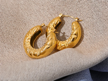 Load image into Gallery viewer, These elegant, chunky hoop earrings are crafted from durable stainless steel with a radiant gold finish, designed to bring a touch of sophistication to everyday looks. Featuring a unique crumpled texture along the edges, they add a modern twist to the classic hoop, making them a standout piece for any occasion. Lightweight yet bold, these hollow hoops are perfect for daily wear and make a thoughtful gift for any woman who appreciates stylish, personalized jewelry.