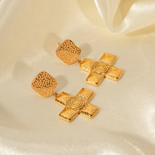 Load image into Gallery viewer, These unique stainless steel earrings feature a hammered spiral design with a striking cross pendant, combining edgy texture with artistic flair. The intricate detailing of the spiral adds depth and movement, making them a standout accessory for any style. Lightweight and durable, these earrings capture a cool, contemporary look that’s perfect for adding personality to everyday outfits or special occasions.