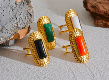 Load image into Gallery viewer, Make a statement with this striking square geometric open ring, featuring a bold, big stone available in four captivating colors: black, red, white, and green. Each stone is beautifully framed by a notched gold edge, adding texture and a luxurious touch to this modern design. Crafted from durable stainless steel and finished with high-quality gold plating, this wide, adjustable ring combines elegance with a contemporary twist, offering a perfect fit and lasting shine.