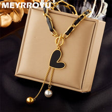 Load image into Gallery viewer, This statement rock glam necklace is made of stainless steel and leather strap. It has nice toggle clasp with a black heart hanging on it. There are two chains hanging from the heart that are endings with a gold and a white pearl. It is a perfect piece for an elegant occasion outfit as well as a nice gift for your special ones.