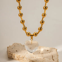 Load image into Gallery viewer, This elegant stainless steel necklace comes in two options, with pink or clear heart pendant. The necklace has a very interesting chain adorned with small stainless steel balls. The heart pendant is made of glass and it makes this necklace a perfect piece for an elegant occasion outfit. The necklace has a lobster clasp and adjustable length.