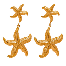 Load image into Gallery viewer, Elevate your summer style with our gold-plated stainless steel starfish dangle earrings, designed for women who love bold and beachy accessories. These high-quality earrings feature an eye-catching drop design with two charming starfish—one smaller and one larger—hanging gracefully below each other for added dimension and movement.