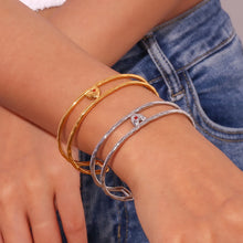 Load image into Gallery viewer, Elevate your style with this charming double layer hollow open bangle bracelet, a stunning piece that adds a touch of romance to any outfit. 18K gold plated for a luxurious finish, this bracelet features a delicate red enamel heart at the center, making it the perfect blend of elegance and playfulness. Available in both gold and silver colors, it's a versatile accessory that can easily complement any look, from casual to chic.