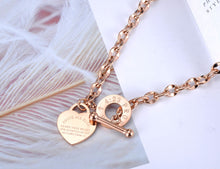 Load image into Gallery viewer,  Stainless steel necklace is coming in two colours: rose gold and silver. Big pedant in the shape of a heart is placed at the bottom part. There is a bible proverb engraved on the heart: "Above all else, guard your heart, for everything you do flows from it." Big toggle clasp with engraved letters makes the necklace even more dominant. 