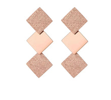 Load image into Gallery viewer, Elegant stainless steel earrings are made in a rose gold colour. They consists of three connected squares. Two are sanded while the middle one has shiny surface. Earrings are rose gold plated and represent perfect and elegant touch to your day to day style. They have stud fastening.