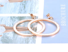 Load image into Gallery viewer, Elegant and classy stainless steel earrings are made in a rose gold colour. Earrings are made of a big circle which hangs on a small cubic zirconia ball. Circles' surface is completely adorned with cubic zirconia. Earrings are rose gold plated and represent perfect and elegant touch to your evening outfit. They have stud fastening.