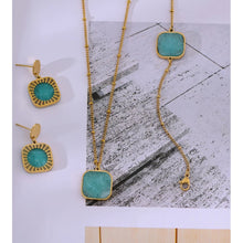 Load image into Gallery viewer, Elegant stainless steel earrings are made in a gold colour. They consists of a small circle on which turquoise natural stone is hanging. The natural stone is circled with gold and carved stainless steel rim. Earrings have real gold plating and represent great accessory to your elegant outfit. They have stud fastening.