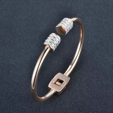 Load image into Gallery viewer, Elegant and luxurious bangle bracelet is made of stainless steel. It comes in two colours: rose gold and silver. It is adorned with rollers on each of its ends. Rollers have lines of embedded cubic zirconia in silver colour. It is a perfect bracelet for glamorous evening.