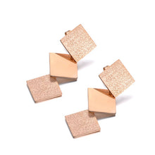 Load image into Gallery viewer, Elegant stainless steel earrings are made in a rose gold colour. They consists of three connected squares. Two are sanded while the middle one has shiny surface. Earrings are rose gold plated and represent perfect and elegant touch to your day to day style. They have stud fastening.