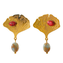Load image into Gallery viewer, Exquisite stainless steel earrings are made in a gold colour. They are made in a shape of a ginkgo leave which is additionally adorned with natural stone. One smaller stone is placed on the leave and can come in red or green colour. Other bigger stone is hanging under the leave and it has turquoise colour. Earrings have real gold plating and represent great accessory to your everyday outfit. They have stud fastening.