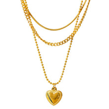 Load image into Gallery viewer, Stainless steel necklace comes in a gold colour and it is three times gold plated. This layered necklace is made of three different chains. The longest one is adorned with a little pedant in a shape of a heart. The heart is decorated with small engraved circles around its border. The chain necklace is perfect for any outfit. It has adjustable length and lobster clasp.