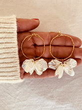 Load image into Gallery viewer, Add a touch of delicate elegance to your look with these minimalistic stud earrings. Featuring thin stainless steel circles adorned with shell flower petals, they offer a perfect blend of modern simplicity and natural beauty. Lightweight and versatile, these earrings are ideal for everyday wear or special occasions, effortlessly complementing any outfit with their subtle charm.
