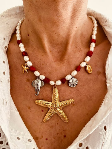 This handmade necklace features a beautiful blend of red and white freshwater and stone pearls, accented with summer-inspired charms. Adorned with a small starfish, a larger starfish, a shell, a silver elephant, and a silver starfish medallion, it captures the essence of coastal charm and sunny days. Perfect for adding a touch of beachy elegance to any outfit.