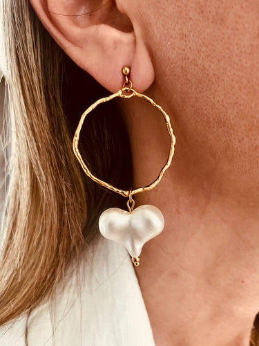 These handcrafted stainless steel earrings showcase a distinctive, irregular hollow circle that hangs gracefully above a vibrant acrylic heart, available in bold red or soft white. The heart dangles elegantly below the circle, creating a playful yet modern contrast that adds a touch of color and movement to any look. Lightweight, durable, and full of personality, these earrings combine geometric precision with artistic flair, making them the perfect accessory to elevate your style for any occasion.