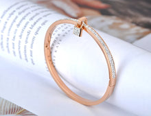 Load image into Gallery viewer, This trendy bracelet features a stunning lock charm adorned with shimmering zircons, set in a rose gold-tone stainless steel bangle for a sophisticated, modern look. The clay pave setting enhances the sparkle of the crystals, adding a luxurious touch to this elegant piece. Perfect as a birthday gift or a stylish addition to any jewelry collection, this bracelet brings a hint of glamour to everyday wear and special occasions alike.
