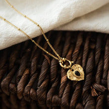 Load image into Gallery viewer, This lovely vintage necklace is made out of stainless steel and is real gold plated. Its chain is adorned with small balls and interesting clasp at the bottom of the necklace. There is a heart pendant hanging on that clasp with a small black stone in the middle. This interesting vintage necklace can be worn with an everyday outfit but also makes a great accessory for evening night out. It has a size adjustable lobster clasp
