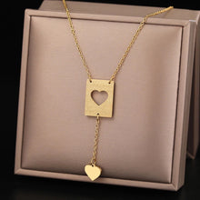 Load image into Gallery viewer, This elegant stainless steel necklace comes in two colours: silver and gold. Its very simple and elegant design is additionally adorned with two pendants: rectangle with a carved heart and a nice heart pendant which hangs from it on a separate chain. It is a perfect piece for an elegant occasion outfit. The necklace has  a lobster clasp.
