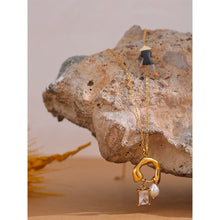 Load image into Gallery viewer, This fashion 18K gold plated stainless steel necklace comes in a gold colour. It is adorned with an interestingly shaped pendant on which we have two smaller pendants hanging: one natural freshwater pearl and one squared cubic zirconia. This simple but trendy necklace is perfect accessory for any outfit due to its minimalistic design. It has lobster clasp and adjustable length.
