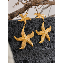 Load image into Gallery viewer, Elevate your summer style with our gold-plated stainless steel starfish dangle earrings, designed for women who love bold and beachy accessories. These high-quality earrings feature an eye-catching drop design with two charming starfish—one smaller and one larger—hanging gracefully below each other for added dimension and movement.
