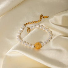 Load image into Gallery viewer, This elegant, vintage-inspired bracelet is crafted from lustrous pearls and features a striking gold-tone hammered stainless steel ball, adding a touch of timeless sophistication. The intricate detailing of the embossed ball beautifully complements the classic pearl design, making this bracelet the perfect accessory for any glamorous or elegant outfit. Finished with a secure lobster clasp and an adjustable chain, it ensures a comfortable and customizable fit. 
