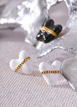 Load image into Gallery viewer, These trendy heart stud earrings feature a chic black or white enamel finish, adorned with a delicate golden chain that adds a unique touch of elegance. Crafted from high-quality 18K plated stainless steel, they exude lasting charm and sophistication. Their romantic design combines classic style with a modern twist, making them a perfect accessory for women who love eye-catching yet versatile jewelry.
