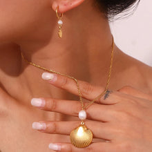 Load image into Gallery viewer, This bohemian stainless steel necklace comes in a 18K plated gold colour. It is adorned with a beautiful shell pendant and a little natural freshwater pearl on top of it. This necklace can perfectly spice up your evening summer outfit . It has lobster clasp and adjustable chain.
