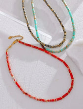 Load image into Gallery viewer, Necklace is made out of big red natural stone beads in a shape of a cilindar. There are small beads in between the red ones made of stainless steel in gold colour. This necklace is a perfect piece for summer elegant outfit. The necklace has a size adjustable chain with a lobster clasp.&nbsp;
