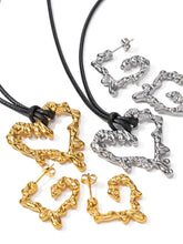 Load image into Gallery viewer, This glam rock necklace is made of gold plated stainless steel pendant which is hanging on a black wax rope. The hollow heart pendant comes in two colours: gold and silver. Its shape imitates lava, which gives the necklace an interesting look. It is a perfect piece for any daily occasion. 
