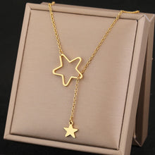 Load image into Gallery viewer, This elegant stainless steel necklace comes in two colours: silver and gold. It is adorned with two star pendants which are positioned at both ends of the chain. Smaller full star pendant needs to be pulled through the star silhouette, which is also the way the necklace should be worn. It is a perfect piece for a daily outfit but can surely spice up evening combination as well. The necklace has lobster clasp.
