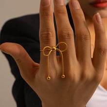 Load image into Gallery viewer, This elegant open slim ring features a charming bow design with delicate tassel accents, crafted from durable stainless steel and plated in radiant 18K gold. Waterproof and stylish, it’s perfect for daily wear or special occasions, offering a blend of sophistication and modern flair. A versatile accessory for women and girls, this new arrival adds a graceful touch to any jewelry collection.
