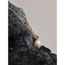 Load image into Gallery viewer, Chic stainless steel necklace comes in a gold colour. It is made of a fine thin chain and it is adorned with two pendants. One is natural pearl and next to it stands small ball in golden colour. This delicate and minimalist necklace will give glam look to every outfit. It has lobster clasp and adjustable length.
