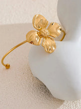 Load image into Gallery viewer, Embrace bold elegance with this stunning charm metal flower cuff bracelet, a statement piece designed to captivate. Featuring an intricate large flower motif, this open bangle is crafted from high-quality stainless steel and plated in radiant 18K gold for a luxurious finish. Its sleek, thin band beautifully contrasts with the striking floral design, creating a unique balance of sophistication and flair.
