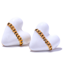 Load image into Gallery viewer, These trendy heart stud earrings feature a chic black or white enamel finish, adorned with a delicate golden chain that adds a unique touch of elegance. Crafted from high-quality 18K plated stainless steel, they exude lasting charm and sophistication. Their romantic design combines classic style with a modern twist, making them a perfect accessory for women who love eye-catching yet versatile jewelry.
