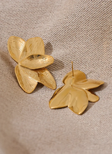 Load image into Gallery viewer, These bold flower stud earrings, crafted from waterproof stainless steel in a radiant gold color, feature large, eye-catching petals that make a high-quality fashion statement. Their oversized floral design offers a touch of elegance and femininity, perfect for adding flair to any outfit. Durable and beautifully crafted, these earrings are ideal for women who appreciate stylish, standout accessories. 
