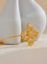 Load image into Gallery viewer, Embrace bold elegance with this stunning charm metal flower cuff bracelet, a statement piece designed to captivate. Featuring an intricate large flower motif, this open bangle is crafted from high-quality stainless steel and plated in radiant 18K gold for a luxurious finish. Its sleek, thin band beautifully contrasts with the striking floral design, creating a unique balance of sophistication and flair.
